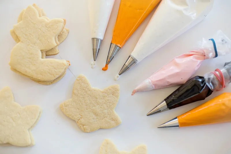 Eine Hand dekoriert präzise einen Kuchen mit einem Spritzbeutel und Zuckerguss, Fokus auf Anwendung.