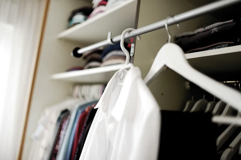 Ein aufgeräumter Kleiderschrank mit perfekt gebügelten und gestärkten Hemden und Blusen.