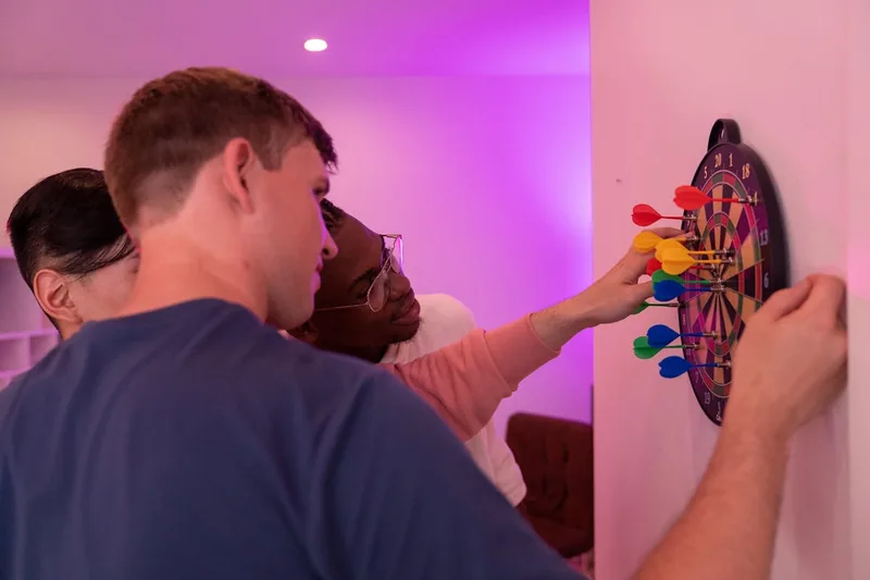 Eine gemütliche Dart-Ecke in einem Spielzimmer, mit beleuchteter Steeldartscheibe und Darts.