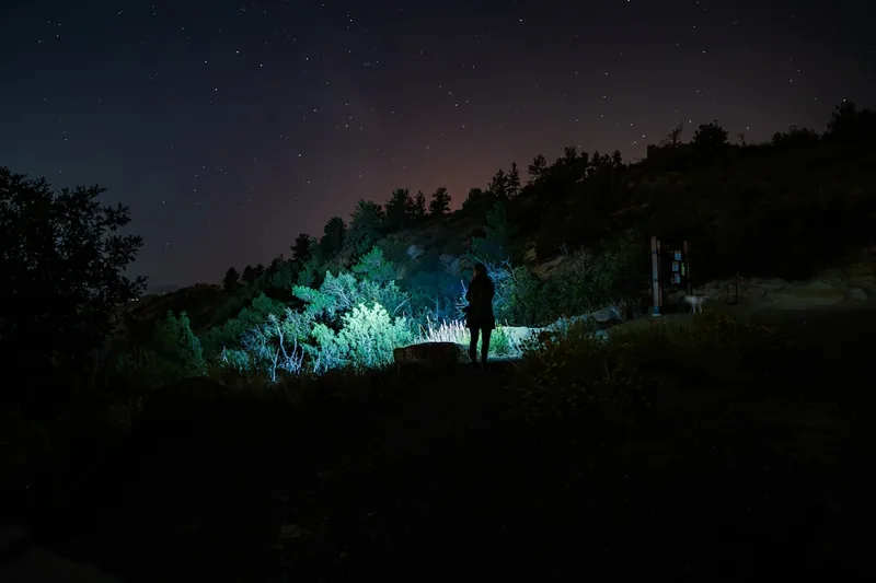 Eine Person trägt eine LED Stirnlampe beim Wandern in der Nacht, der Lichtkegel ist sichtbar.