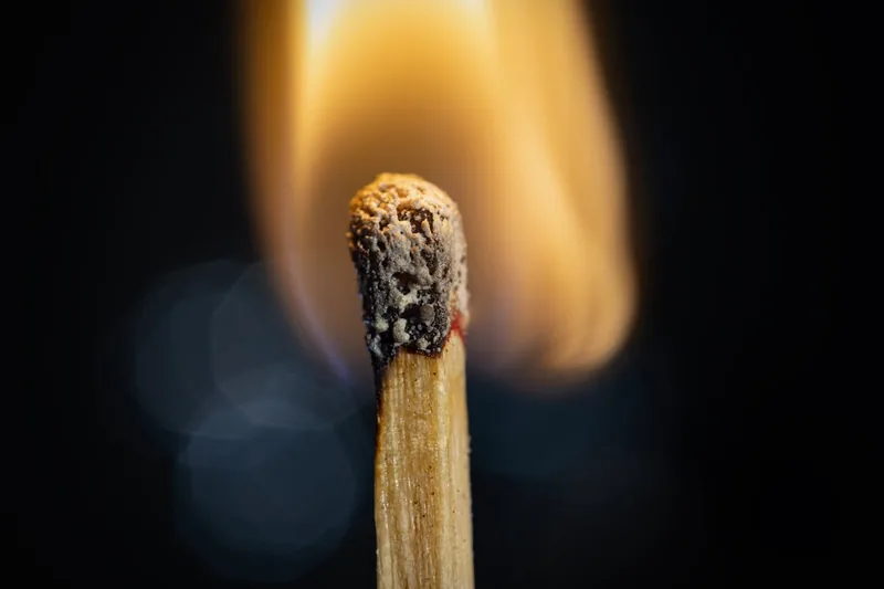 Ein entzündetes Streichholz mit heller Flamme, das die korrekte Handhabung und das Anzünden von Streichhölzern illustriert.