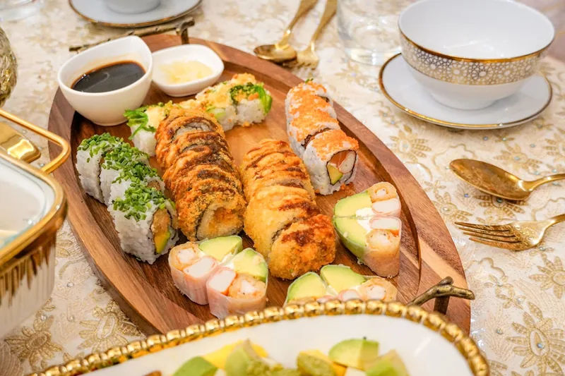 Ansprechend angerichtetes Sushi auf einem Esstisch, umgeben von Saucen und Dekor.