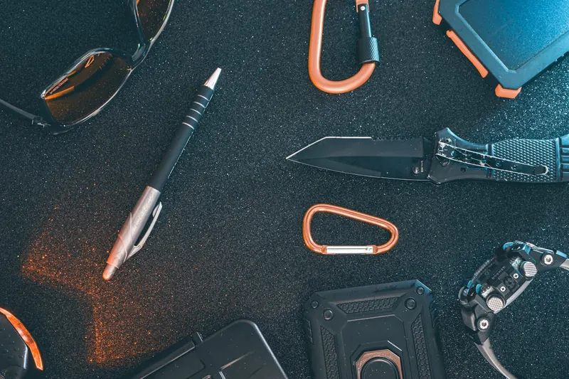 Ein Ensemble von EDC-Gegenständen, inklusive Tactical Pen, auf einer Holzoberfläche arrangiert.