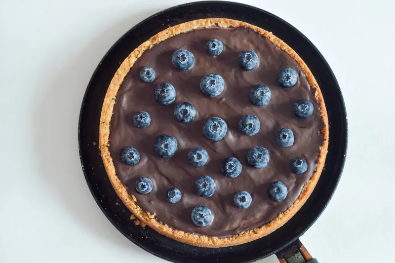 Hände einer Person, die Teig in eine Tarteform drückt und vorbereitet für süße oder herzhafte Tartes.