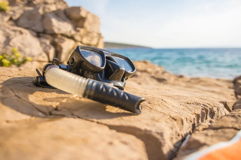 Sommerliche Urlaubsstimmung am Strand mit Tauchmaske und Schnorchel im Sand, bereit für ein Abenteuer.