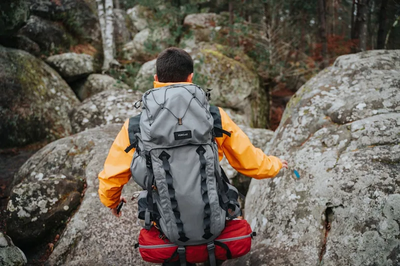 Eine Person trägt einen funktionalen Outdoor Rucksack beim Wandern, um seine praktische Anwendung zu zeigen.