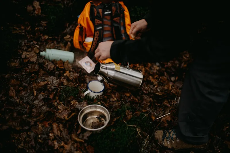 Eine Thermoflasche steht in einem Rucksack in einer malerischen Berglandschaft, bereit für die Wanderung.