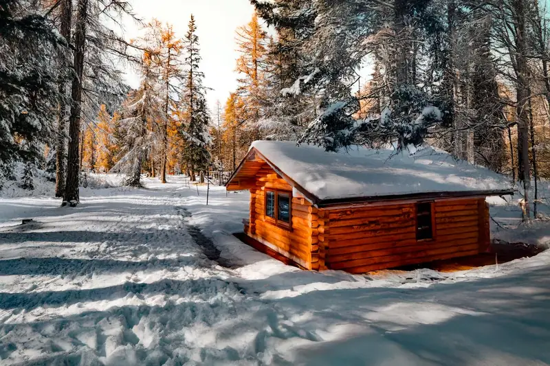 Gemütliche Winterlandschaft durchs Fenster einer warmen Hütte, ideal zum Entspannen nach Outdoor-Aktivitäten.