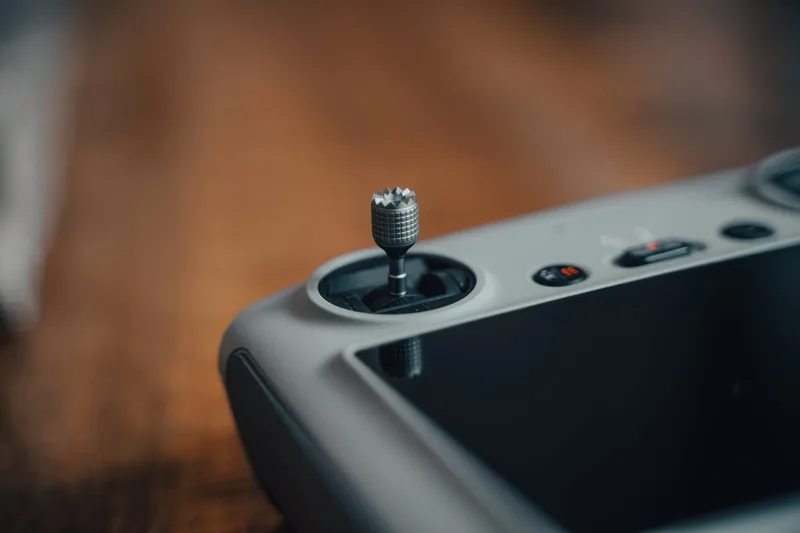Nahaufnahme der Bedienelemente eines Joysticks, zeigt Tasten, Schalter und präzise Verarbeitung.