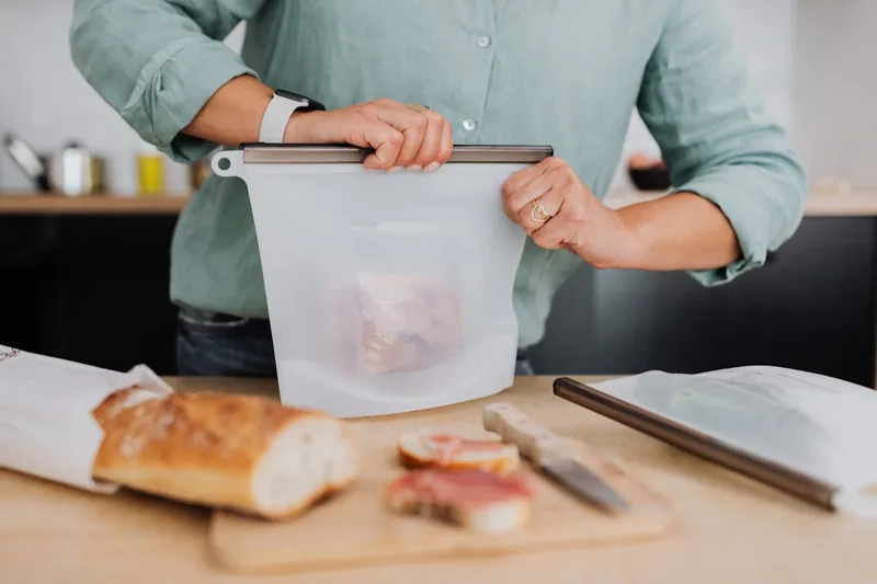 Eine Person füllt eine frisch zubereitete Mahlzeit in eine Tiefkühldose, bereit zum Einfrieren und Aufbewahren.
