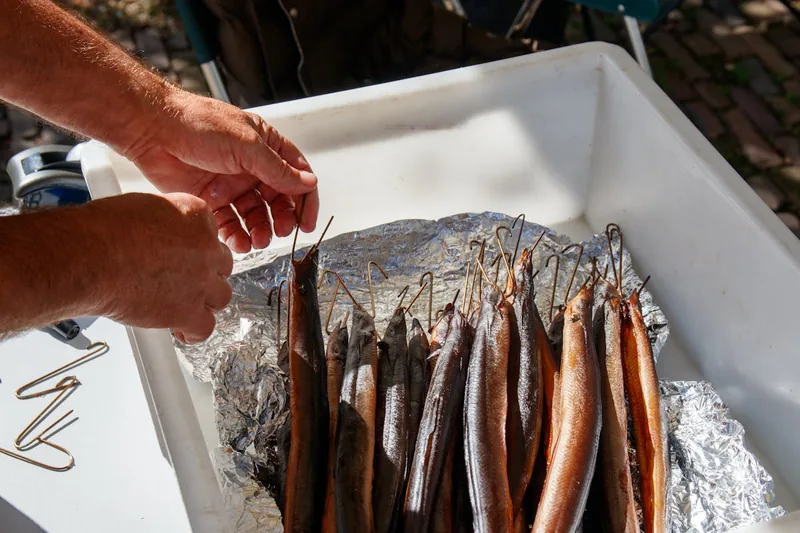 Eine Person legt frisch gefangenen Fisch in einen Tischräucherofen zum Garen.