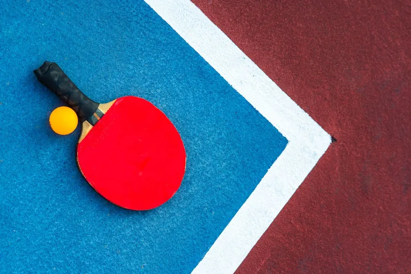 Eine Hand hält einen Tischtennisschläger während des Spiels, bereit für den nächsten Schlag.