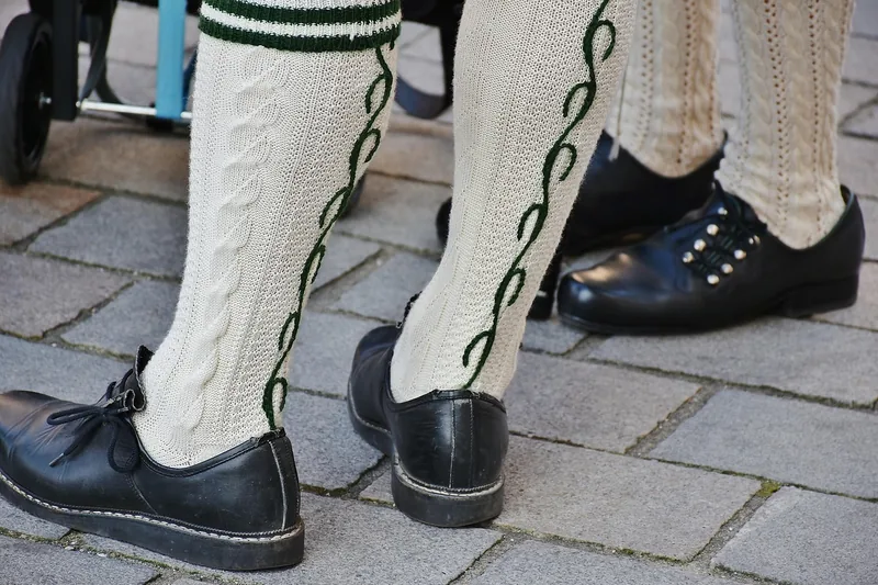 Ein Herr präsentiert stolz seine Trachtenschuhe, kombiniert mit einer traditionellen Lederhose.