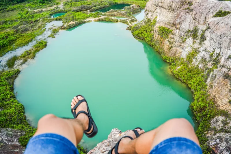Malerische Berglandschaft im Sommer, ein Paar Trekkingsandalen ruht im Vordergrund auf einem Felsen.
