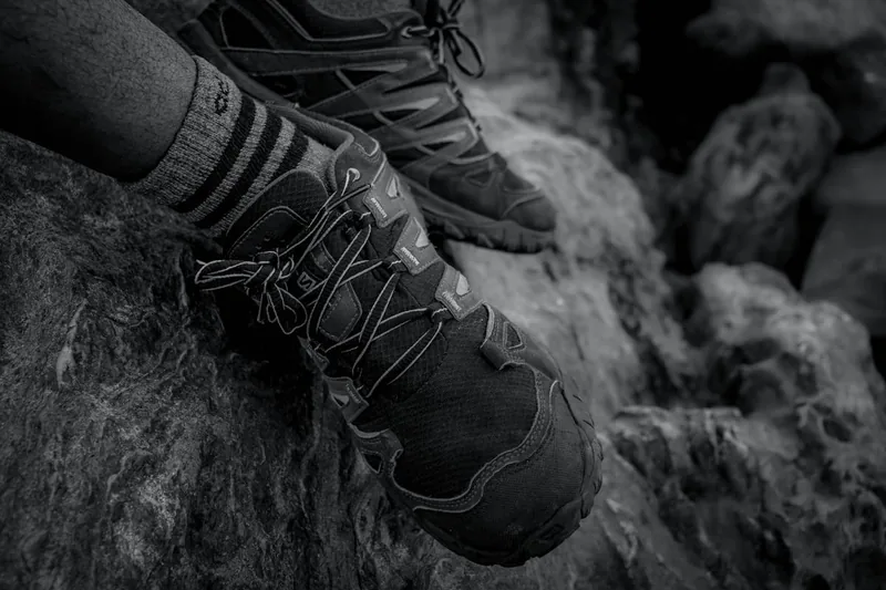 Eine Person beim Wandern, der Fokus liegt auf den Trekkingschuhen, die einen felsigen Pfad begehen.