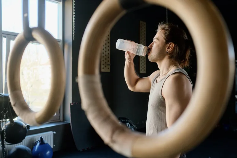 Eine Person trinkt während des Sports im Fitnessstudio aus einer BPA-freien Trinkflasche, aktiv im Einsatz.