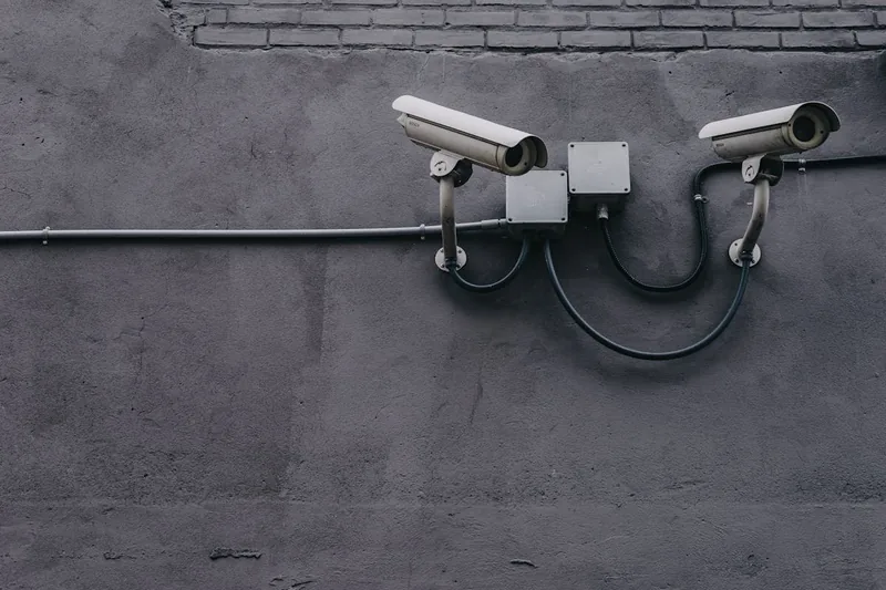 Hände installieren eine Überwachungskamera an der Wand, als Teil eines Sicherheitssystems.