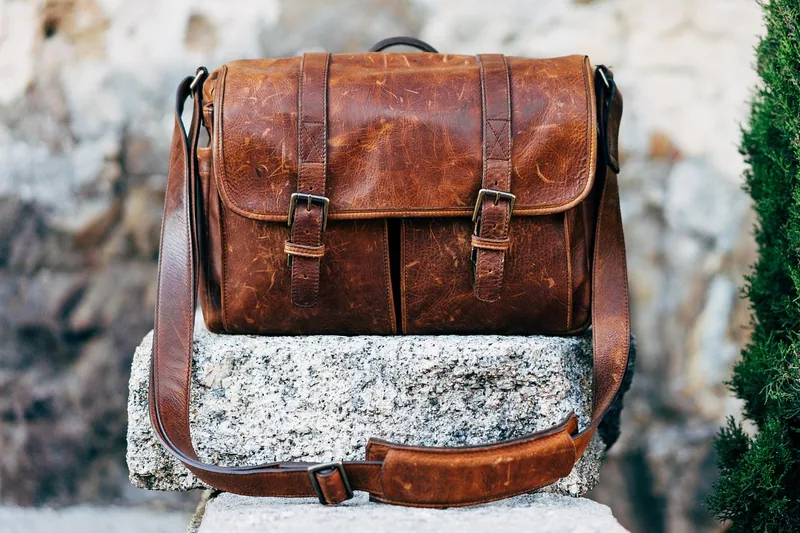 Hochwertige braune Leder-Umhängetasche im Vordergrund, klar und elegant präsentiert.
