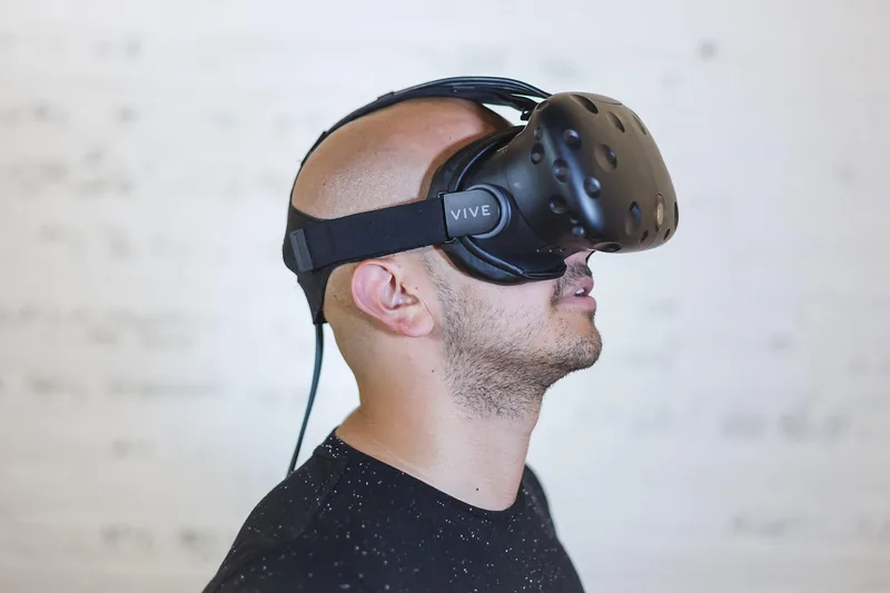 Eine Person (Rückenansicht oder Seitenprofil) mit Virtual Reality Brille und Controllern in Aktion beim Spielen.