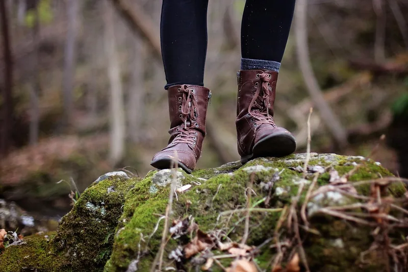 Eine Person zieht Wandersocken an, bereit für die Wanderung, im Hintergrund verschwommene Naturkulisse.