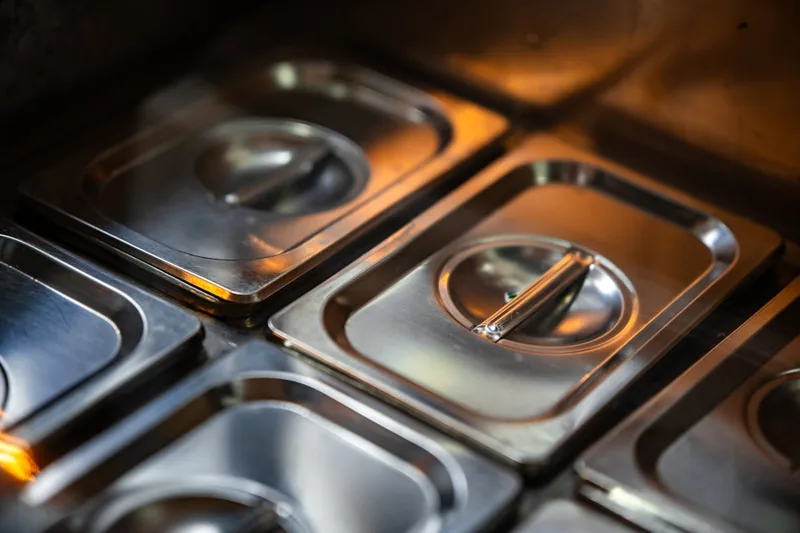 Detailaufnahme der gebürsteten Edelstahloberfläche einer professionellen Warmhalteplatte, reflektierend und hygienisch.