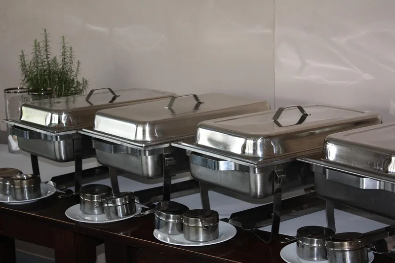 Eine professionelle Catering-Station in einer Restaurantküche mit mehreren warmgehaltenen Speisen in einer Warmhalteplatte.