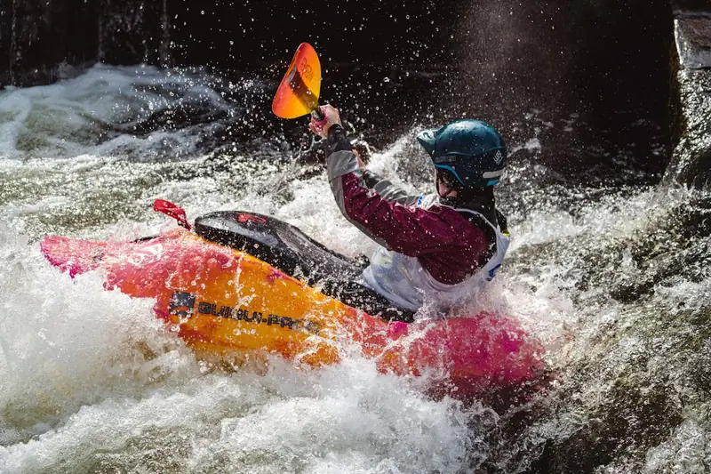 Eine Person nutzt eine wasserdichte Tasche beim Kajakfahren auf einem Fluss, schützt Wertsachen vor Spritzwasser.