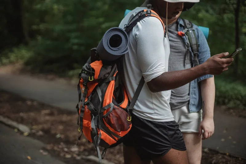 Eine Person trägt einen wasserdichten Rucksack beim Wandern auf einem feuchten Waldweg.