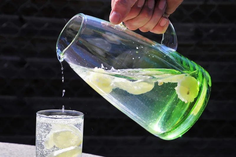 Eine Hand füllt ein Glas mit gefiltertem Wasser aus einer Filterkanne.