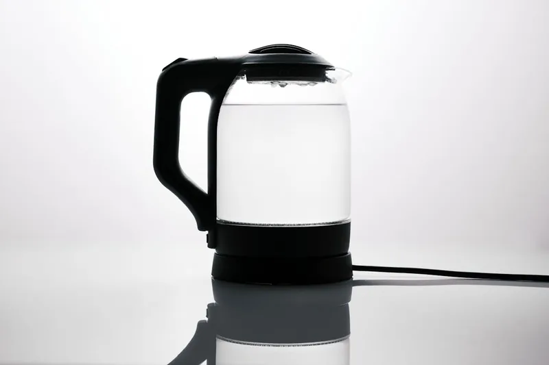 Eine Person gießt Wasser aus einem eleganten Design-Wasserkocher in eine Tasse, demonstriert die einfache Handhabung.