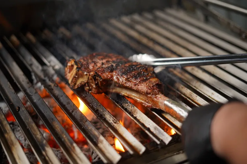Ein hochwertiger Grill im Vordergrund, elegant und funktional, bereit für den Einsatz im Garten.