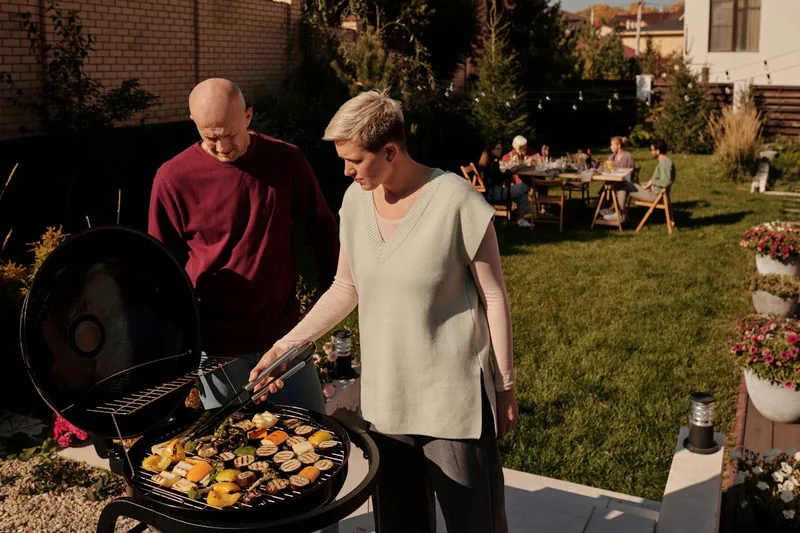 Gemütliche Gartenszene mit Freunden und Familie, die gemeinsam einen schönen Grillabend genießen.