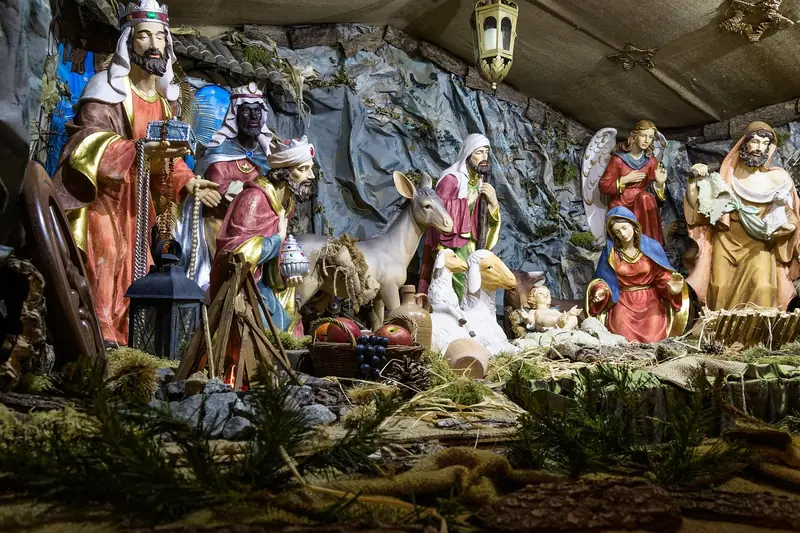 Eine Person arrangiert liebevoll die Figuren in einer Weihnachtskrippe, um sie zu präsentieren.