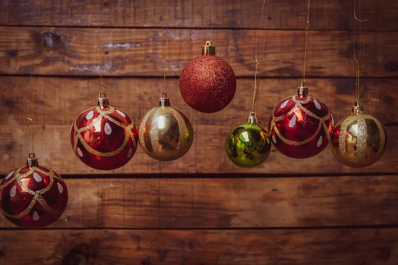 Ein Set glänzender roter Weihnachtskugeln in verschiedenen Größen, vor neutralem Hintergrund als Produktfoto.