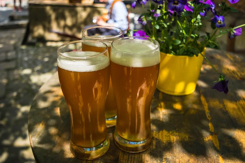 Gemütliche Biergarten-Atmosphäre mit mehreren gefüllten Weizengläsern auf einem Holztisch.