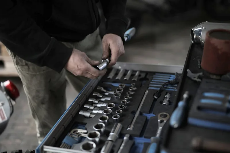 Eine Hand, die ein Werkzeug aus einer bestückten Werkstattwagen Einlage entnimmt oder hineinlegt.