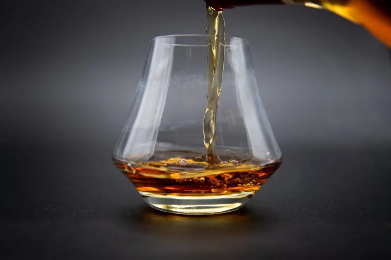 Nahaufnahme des bernsteinfarbenen Whiskys in einem Tumbler, fokussiert auf Farbe und Textur.