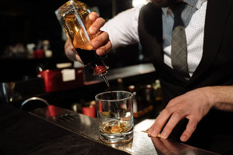 Eine Hand hält ein edles Whiskyglas, während Whisky eingegossen wird, im Gebrauch.