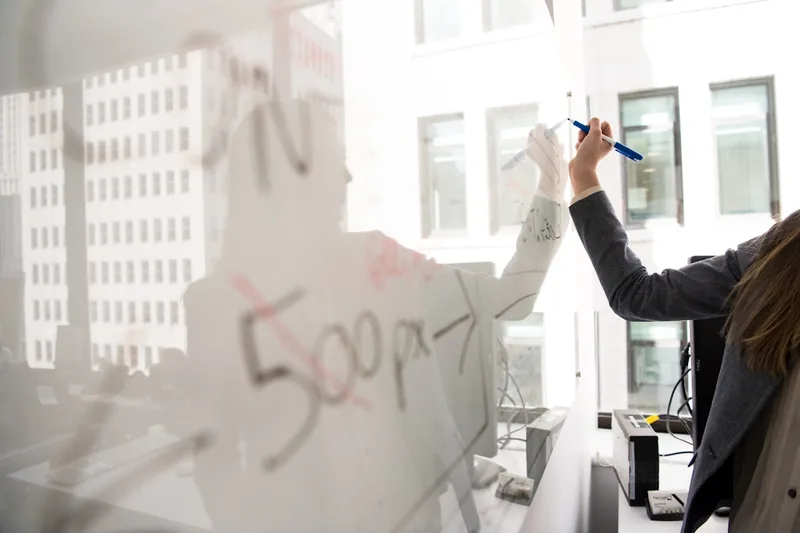Eine Person schreibt mit einem Marker Ideen und Notizen auf ein mobiles Whiteboard.