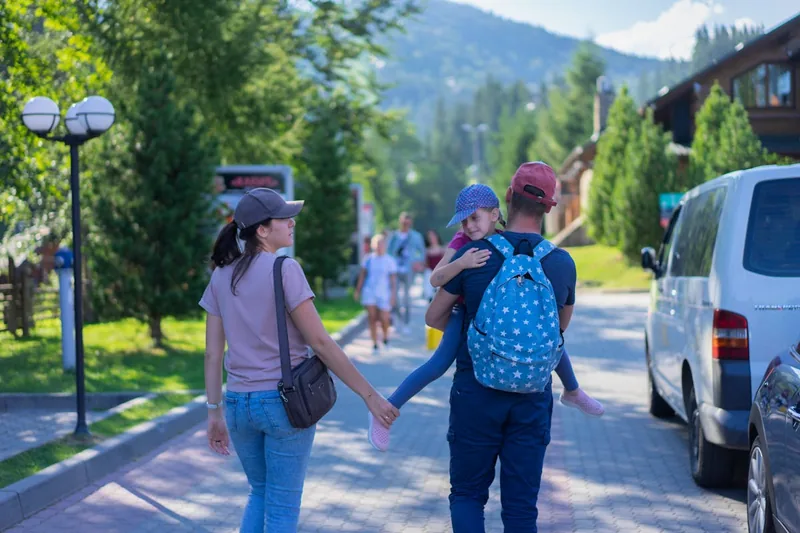 Elternteil öffnet einen Wickelrucksack, um Babysachen unterwegs im Park zu entnehmen, im Alltagseinsatz.