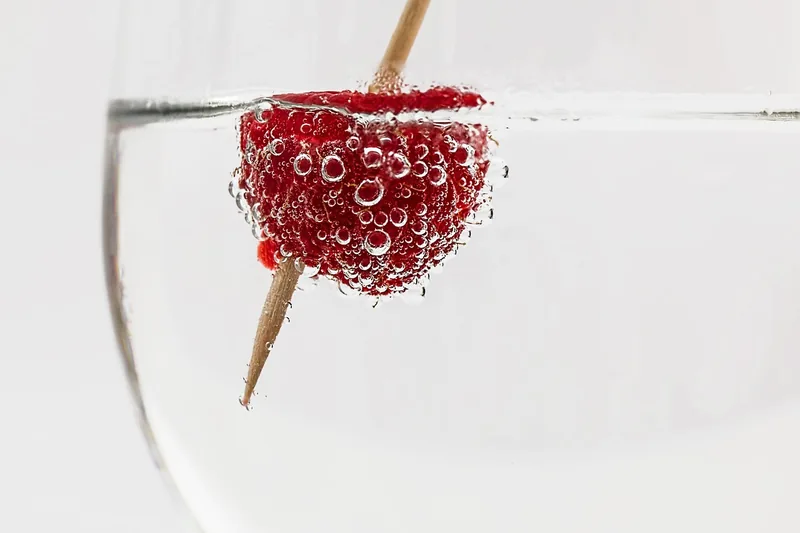 Eine anonyme Hand gießt klaren Wodka in ein Glas mit Eis, bereit für einen Cocktail.