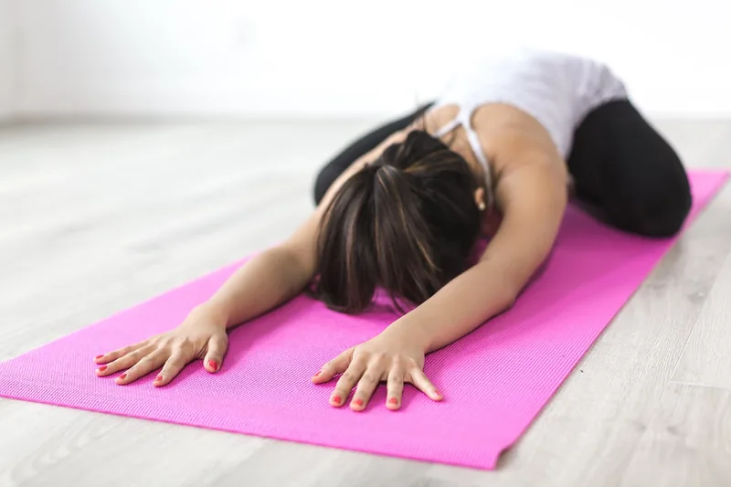 Eine Person praktiziert Yoga auf einer rutschfesten Yogamatte in einer ruhigen Innenumgebung.