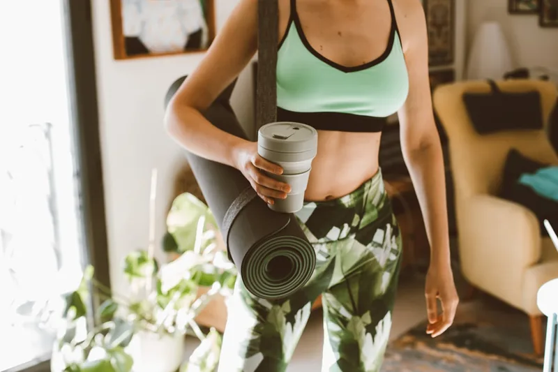 Eine Person packt eine Yogamatte in eine umweltfreundliche Yogatasche, bereit für die nächste Yogastunde.