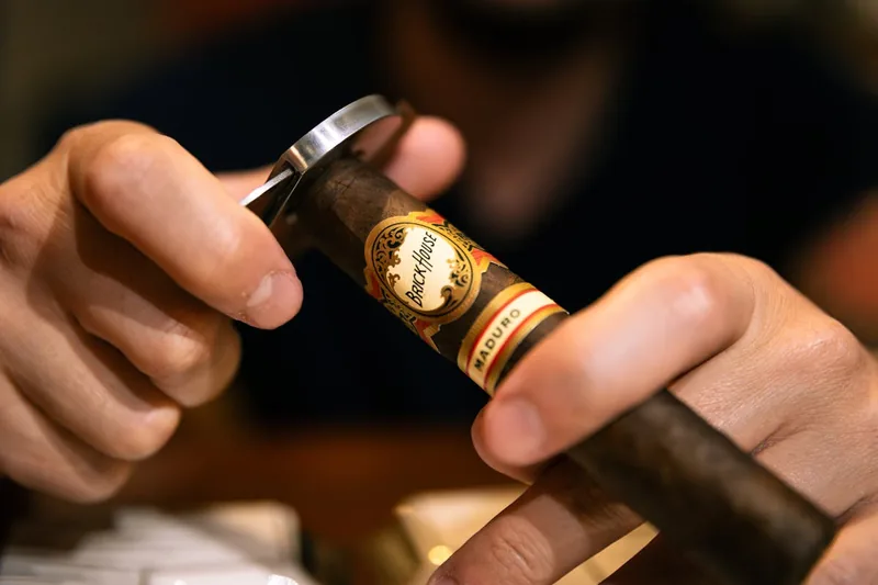Eine Hand entnimmt vorsichtig eine Zigarre aus einem geöffneten Zigarren-Humidor, bereit für den Genuss.