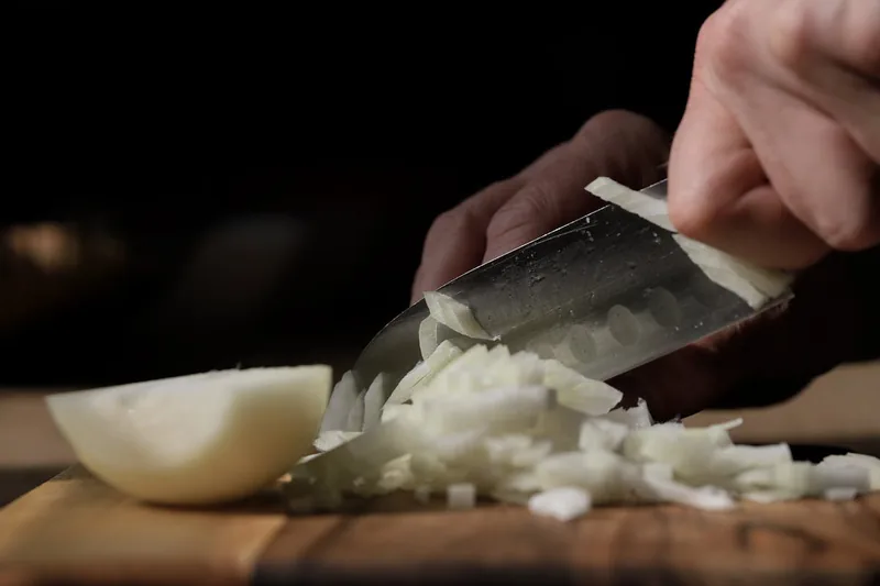 Nahaufnahme der scharfen Klingen und des Behälters eines Zwiebelschneiders aus Kunststoff und Edelstahl.