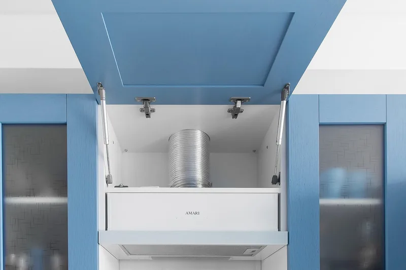 Eine Person beim Kochen am Induktionskochfeld, darüber die unauffällige Zwischenbauhaube in Betrieb.
